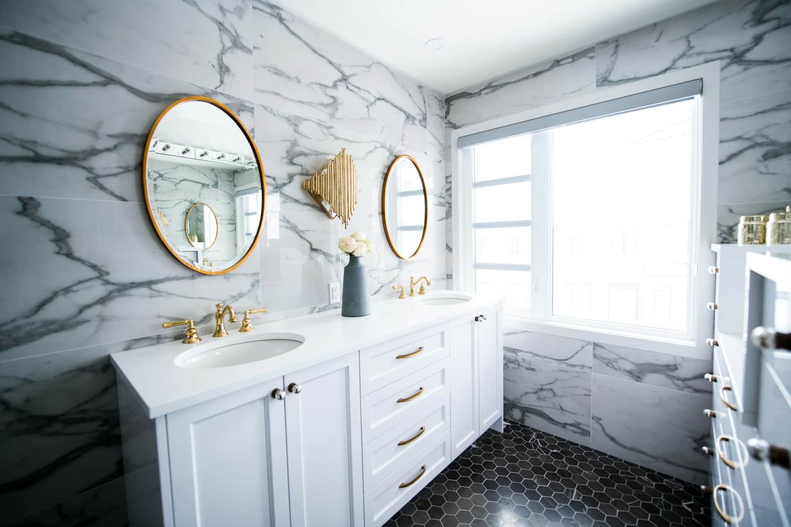 Renovated bathroom with double vanity, brass fixtures, and hex tile floor