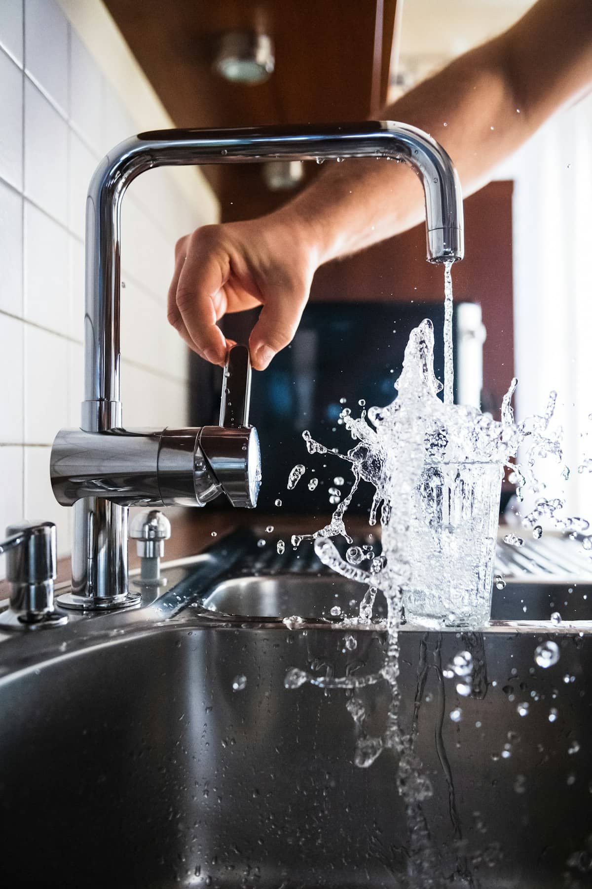 Hand testing water flow at a kitchen faucet with strong splash